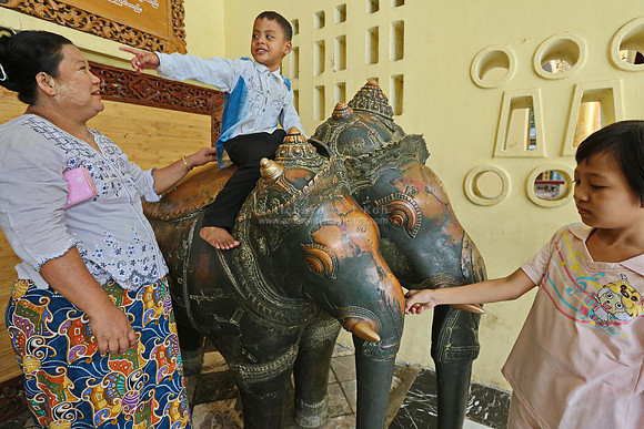 Mandalay Mahamuni Paya boy sitting on Khmer bronze statue of Airavata