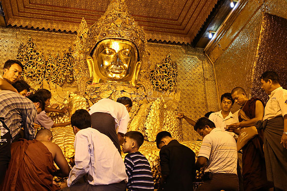 Mandalay Mahamuni Paya men devotees pasting gold foil on Mahamuni Buddha